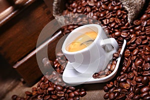 Fresh roasted coffee beans in burlap sack, espresso in cup and grinder on stone background.