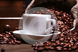 Fresh roasted coffee beans in burlap sack, espresso in cup and grinder on stone background.