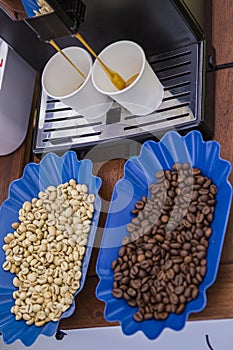 Fresh and roasted coffee beans and coffee machine preparing coffee