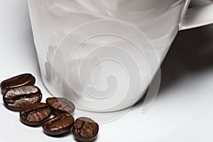 fresh roasted coffee beans on a white clean saucer next to a cup of espresso
