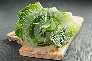 Fresh romain green salad leaves on olive board