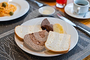 Fresh romantic breakfast table next to morning briliant light window, with bread, pastry, spaghetti, fruit, juice, coffee cup