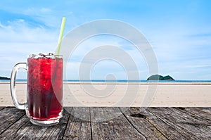 Fresh Roselle juice sweet water and ice in glass iced coffee on table wooden with beach landscape view nature background ,Summer