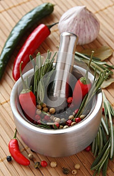 Fresh rosemary herb and red pepper in metal mortar with pestle