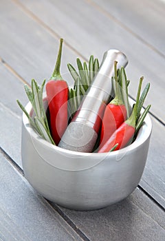 Fresh rosemary herb and red pepper in metal mortar with pestle