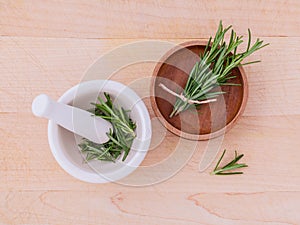 Fresh rosemary herbal medicine in mortar and wooden bowl on wood