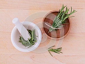 Fresh rosemary herbal medicine in mortar and wooden bowl on wood