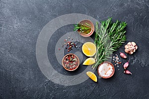 Fresh rosemary and mixed spices on black stone table top view. Ingredients for cooking. Food background.
