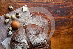 Fresh round homemade rye bread wrapped in baking paper and cotton gauze, colored chicken and quail eggs