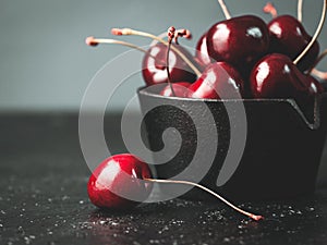 Fresh ruby cherries on black background. Dark moody close up still life