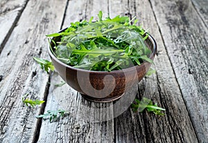 Fresh rucola in a bowl on a rustic wooden table.