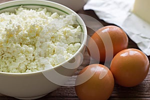 Fresh rustic cottage cheese and eggs on wooden background, baking ingredients