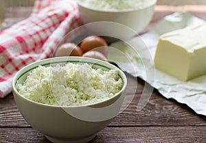 Fresh rustic cottage cheese and eggs on wooden background, baking ingredients