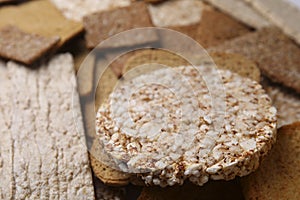 Fresh rye crispbreads, crunchy rice cakes and rusks as background, closeup