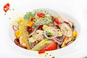 Fresh salad with avocado, sun dried tomatoes, hot peppers, cherry tomatoes, sweet peppers and onion on wooden background close up