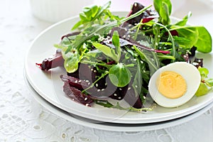 Fresh salad with beetroot, mix leaves, olive oil, egg and sesame seeds