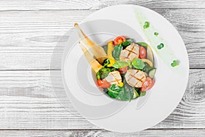 Fresh salad with chicken breast, baby spinach, basil, cherry tomatoes, pear, cucumber on plate on wooden background close up