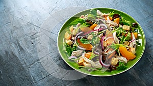 Fresh salad with chicken breast, peach, red onion, croutons and vegetables in a green plate. healthy food