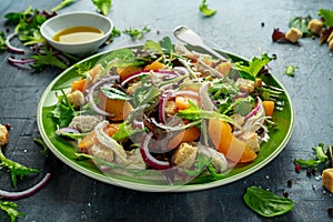 Fresh salad with chicken breast, peach, red onion, croutons and vegetables in a green plate. healthy food