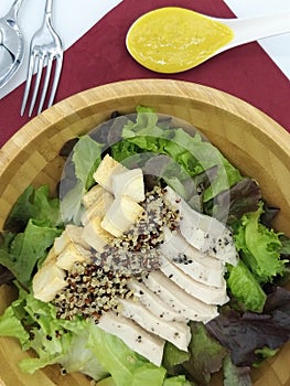 Fresh salad with chicken breast quinoa, baked bread in a wooden Tray And pumpkin salad dressing on the red cloth isolate white