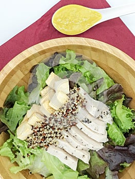 Fresh salad with chicken breast quinoa, baked bread in a wooden Tray And pumpkin salad dressing on the red cloth isolate white