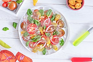 Fresh salad with colorful tomatoes, cheese, onion and spinach on a white background. Top view