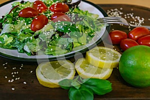 Fresh salad from different kinds of greens and a cherry tomato, dressed with olive oil and sprinkled with sesame seeds