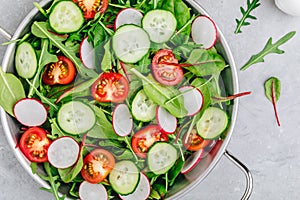 Fresh salad with green leaves of arugula, , spinach, beets, radish, cucumber and tomato on a gray stone background photo