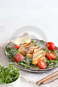 Fresh salad with grilled halumi cheese, cherry tomatoes and arugula. copy space