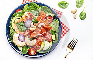 Fresh salad for keto diet with shrimp, salmon, avocado, spinach, cucumber, tomato, cashew nuts, sesame. Low-carbohydrate lunch