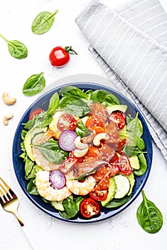 Fresh salad for keto diet with shrimp, salmon, avocado, spinach, cucumber, tomato, cashew nuts, sesame. Low-carbohydrate lunch