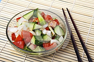 Fresh salad from organic natural vegetables and chopstick on bamboo mat. Chinese or japanese kitchen concept. Copy space