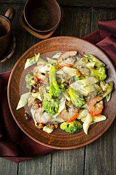 Fresh salad plate with shrimp, penna pasta, avocado and arugula on wooden background flat lay. Healthy food.