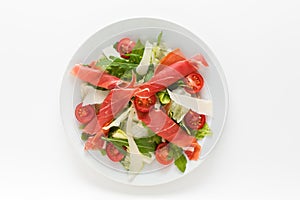 Fresh salad with prosciutto ham, parmesan and cherry tomatoes top view on a white background