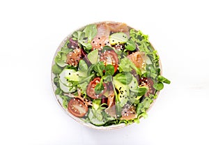 Fresh salad with salted salmon, avocado, cucumber, sesame seeds, olive oil, tomatoes and mixed herbs. White background, top view,