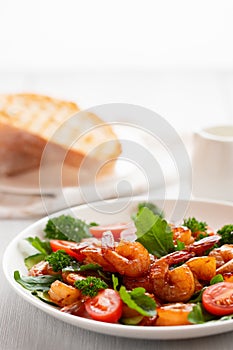 Fresh salad of shrimps, tomatoes, arugula and herbs on a white plate. vertical image