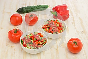 Fresh salad of sliced green cucumbers, red tomatoes and bell peppers on wood table. Vegetables. Gluten-free, lactose-free vegan