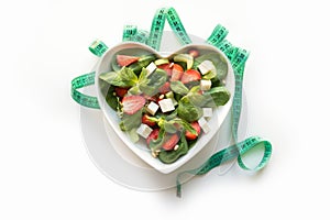 Fresh salad of strawberry, celery, spinach, pine nuts, cheese in plate as heart on white. Concept clean eating for Detox