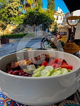 Fresh salad with tomatoes, cheese and greens on the table of street cafe. Healthy food concept