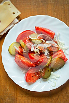 Fresh salad with tomatoes, gherkin and onion, served with ham and cheese sandwich