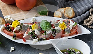 Fresh salad of tomatoes and mozzarella. Recipe with olive oil with red onion, olives and basil