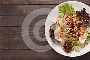 Fresh salad on the wooden background. Top view