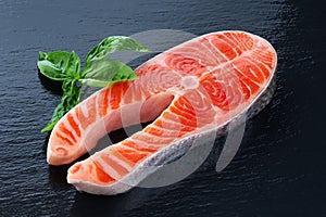 Fresh salmon with basil on a dark background