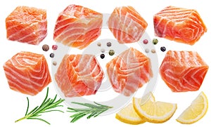 Fresh salmon cubes or salmon pieces with spices and lemon slices on white background. File contains clipping path