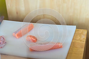A fresh salmon on a cutting board, Japanese chef in restaurant slicing raw salmon, ingredient for seafood dish. Chef with a knife