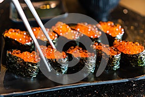 Fresh Salmon eggs sushi or ikura in japanese style in ceramic black plate on black marble table