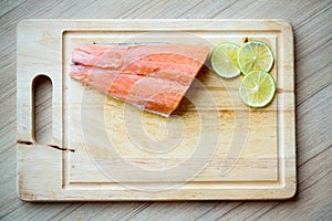 Fresh salmon, lemon slice on wood chopping board. image for background