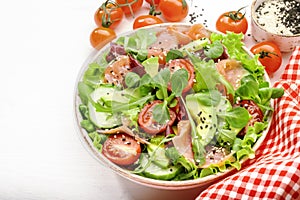 Fresh salmon salad with avocado, cucumber, sesame seeds, olive oil, tomatoes and mixed herbs. White background, top view