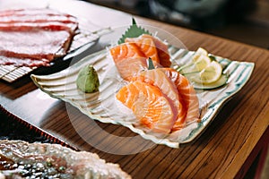 Fresh salmon sashimi served with wasabi, sliced lemon and cucumber