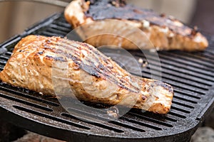Fresh Salmon steak cooking on iron grates over flaming charcoal photo